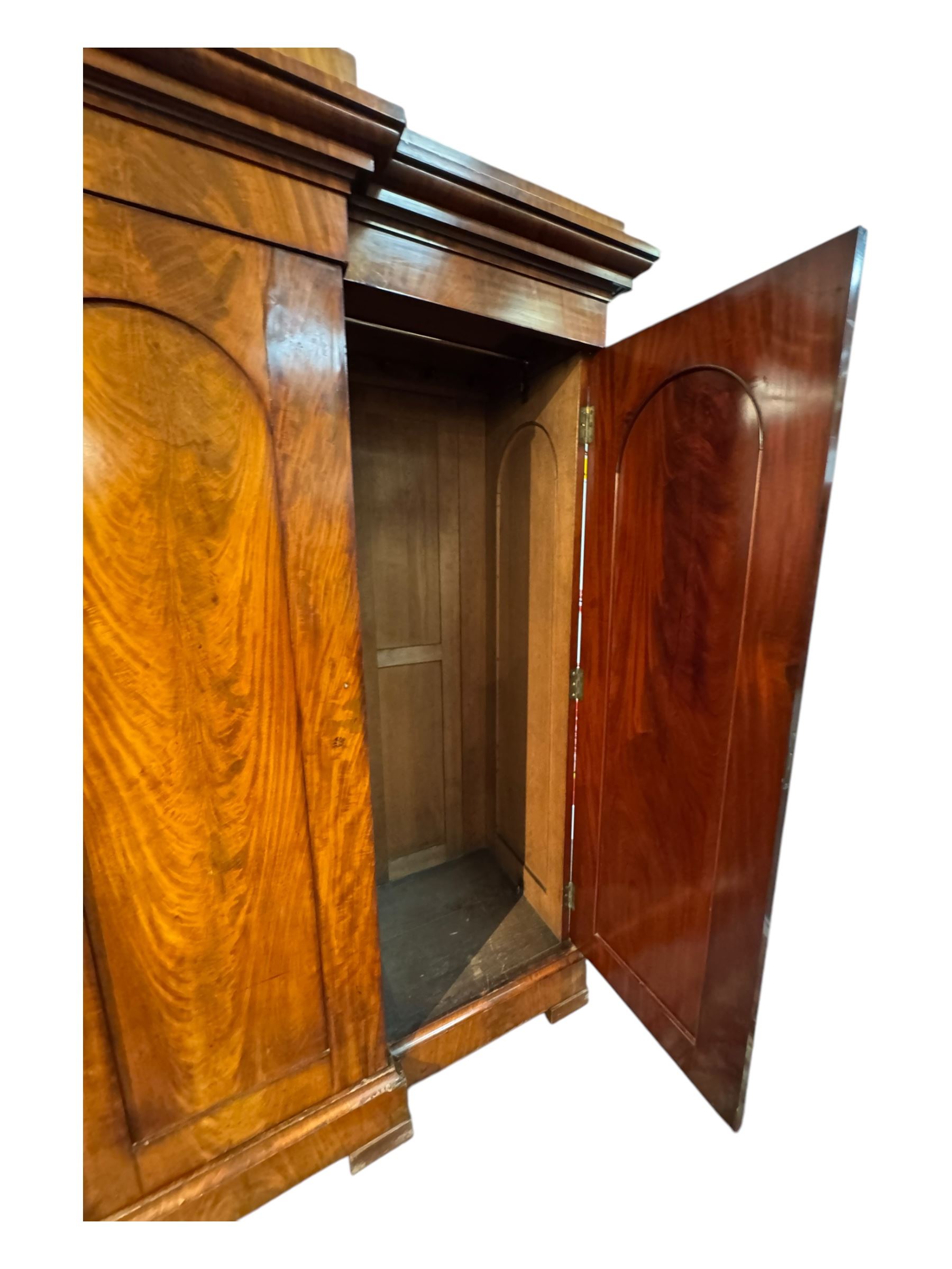 19th century mahogany break-fronted quadruple wardrobe, stepped and moulded projecting cornice over four arch panelled doors, moulded plinth base on blocks 