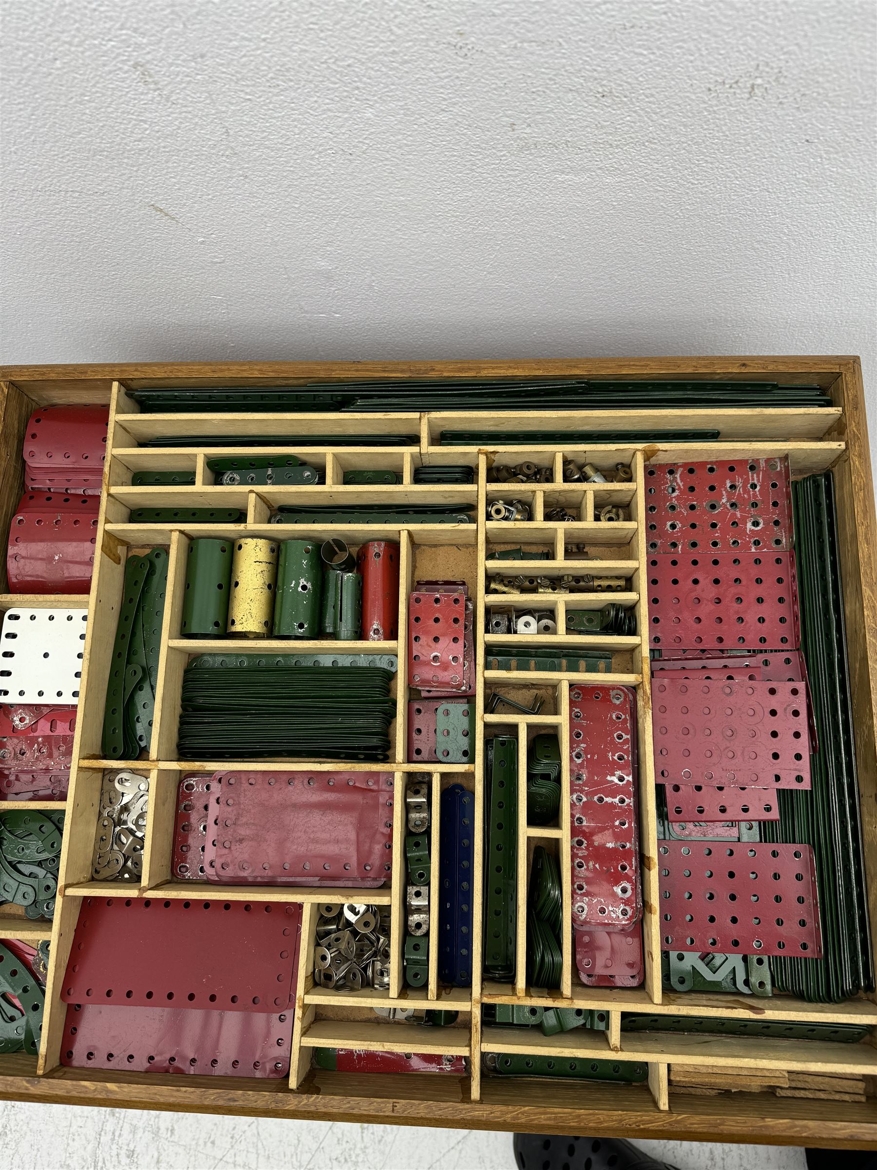 Large collection of Meccano, including perforated strips, wheels, cogs, nuts and bolts, various Meccano instruction manuals and magazines, all housed within a modified wooden box, with three tiered compartmentalised sections and upon four twist legs, box H60cm