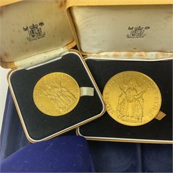 Two Isle of Man one pound coins in cases with certificates, three Queen Elizabeth II 1952-1977 Silver Jubilee commemorative medallions, an empty coin box and a Queen Mother commemorative five pound coin, in a blue coin display case