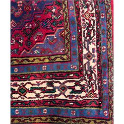 Northwestern Persian Hamadan hand-knotted rug, madder red field with a lozenge medallion enclosing an ivory centrepiece, indigo spandrels within an ivory border of stylized floral motifs between multiple guard borders 