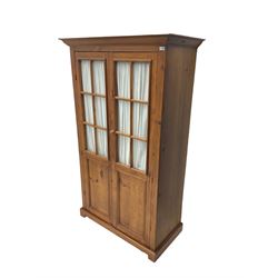 Rustic waxed pine double wardrobe, glazed doors with interior curtain, enclosing hanging rail, on bracket feet