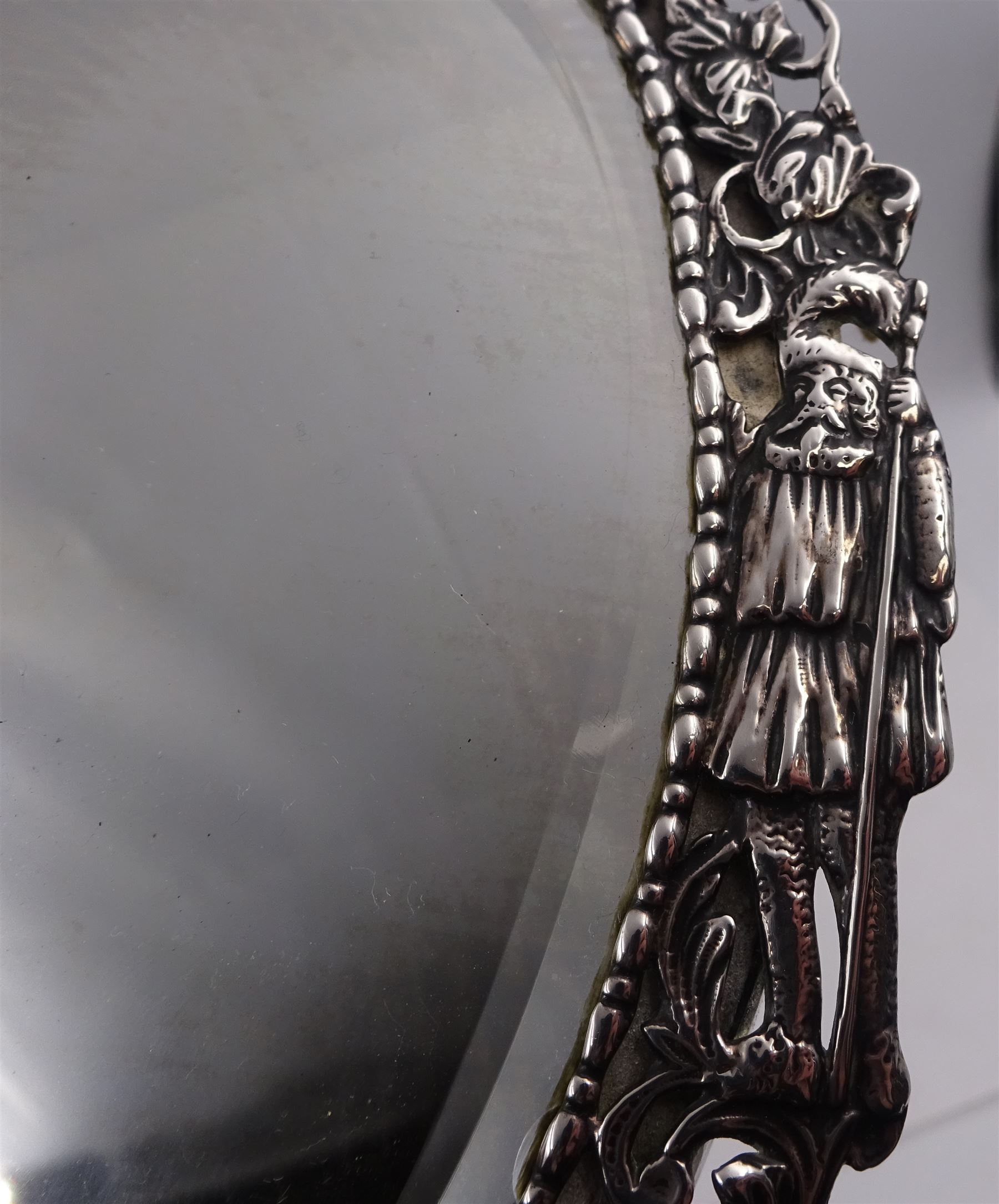 Continental silver miniature dressing table/wall mirror, of oval form with bevelled mirror plate, surrounded by a bead and dart rim, with pierced scrolling floral border with a standing cavalier to either side and the bust of a cavalier to the base, H17.7cm