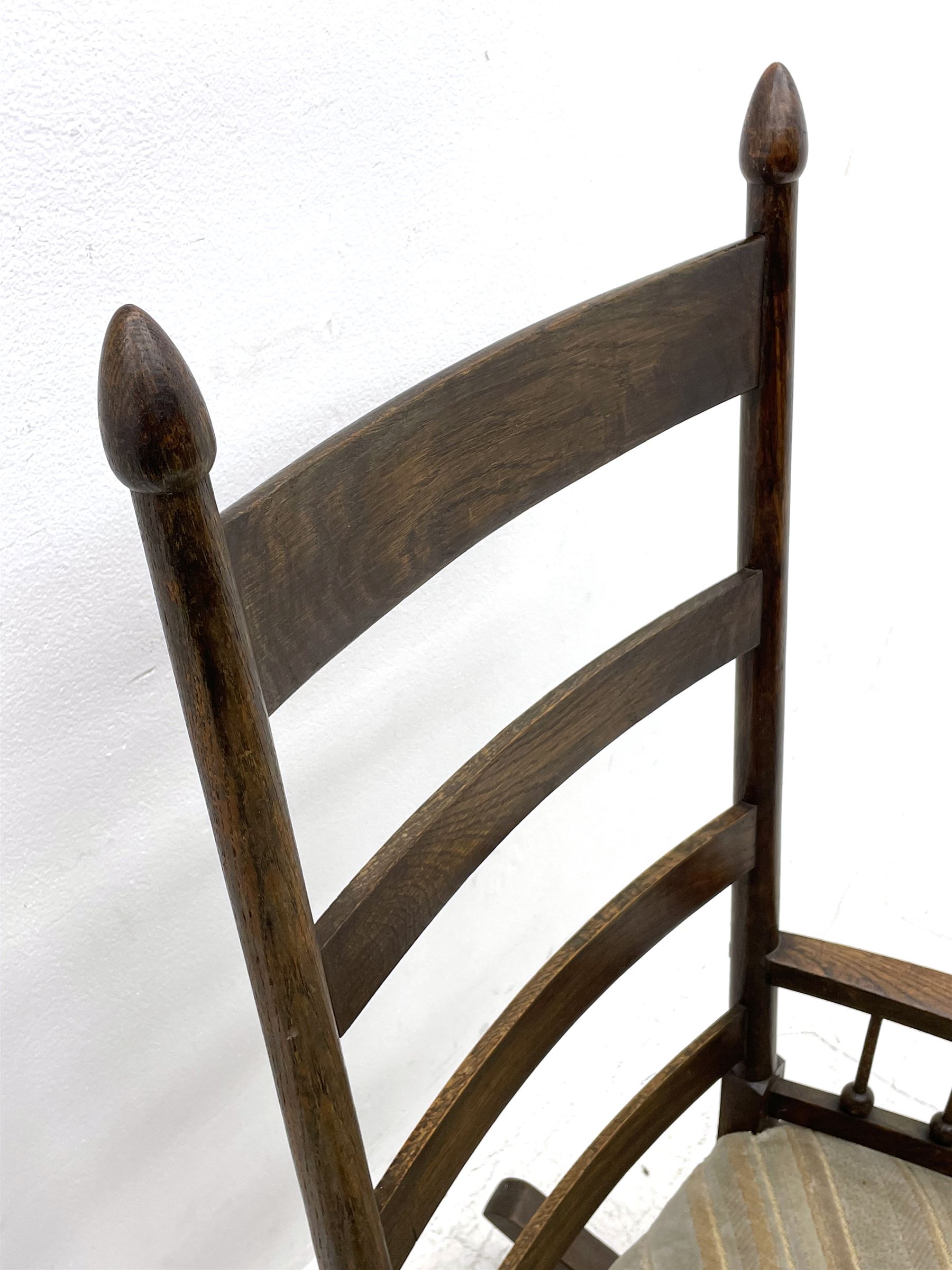 William Birch for Liberty & Co. - Arts and Crafts period oak ladder back rocking chair, the arms supported by a series of turned spindles, upholstered seat