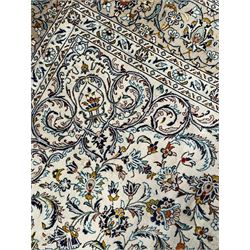 Persian Kashan ivory ground carpet, central pole medallion surrounded by swirling leafy branches and stylised plant motifs, scrolled foliate spandrels, the main border decorated with scrolling pattern and repeating palmettes, within floral patter guard stripes 