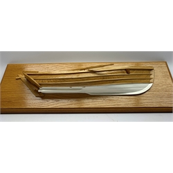 Half block model of a coble made from elm and oak with rudder, loose mounted oar and white painted keel, on oak finish board W63cm
