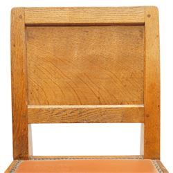 Mouseman - pair of 1940's adzed and panelled oak chairs, the rectangular adzed back-panel over seats upholstered in orange-tan leather with studwork, raised on turned octagonal supports united by box stretcher, with carved mouse signature, by the workshop of Robert Thompson of Kilburn
Provenance: purchased directly from the Kilburn workshop in the late 1940s