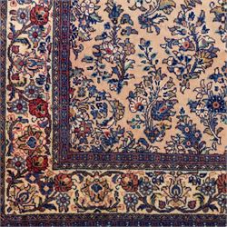 Central Persian Nain hand-knotted rug, ivory ground decorated with a central lobbed medallion and an all-over floral and foliate design of stylised palmettes, flowering plants, and scrolling vine work, enclosed by a contrasting main border with repeating floral motifs, flanked by multiple guard borders, with cotton fringe ends 