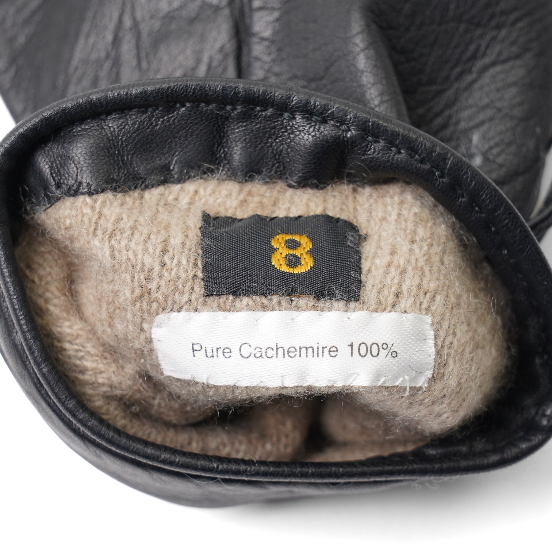 Hermès - pair of black leather gloves, lined in 100% cashmere, with pierced oval leather strap detail to cuffs, size 8