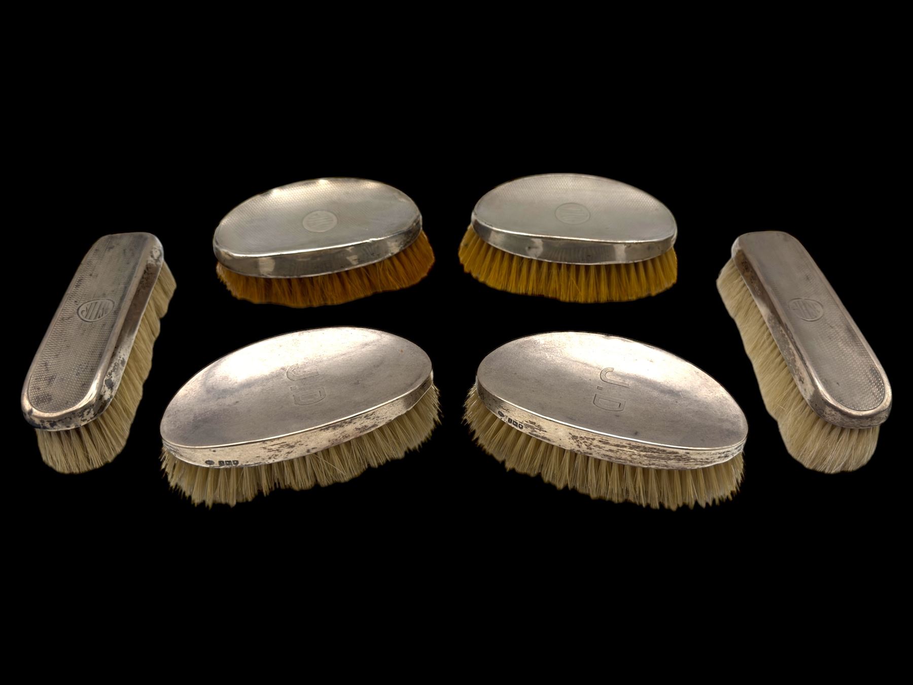 Six silver mounted dressing table brushes, comprising set of four, with engine turned decoration and engraved monogram and a pair of oval brushes with engraved initials, all hallmarked