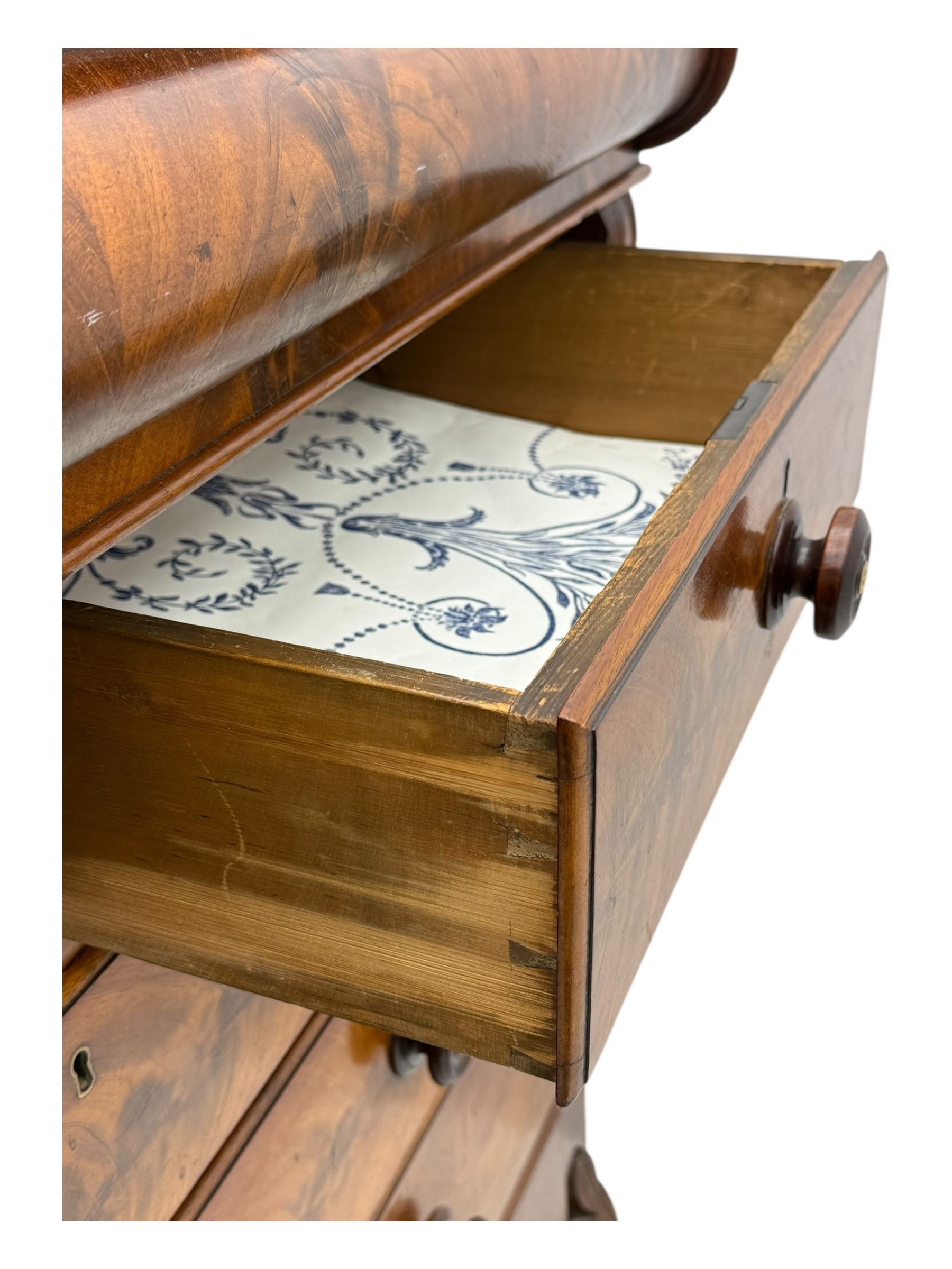 19th century flame mahogany Scotch chest, frieze long drawer above two short and four long graduating drawers, with turned knobs scrolled carved side bracket 