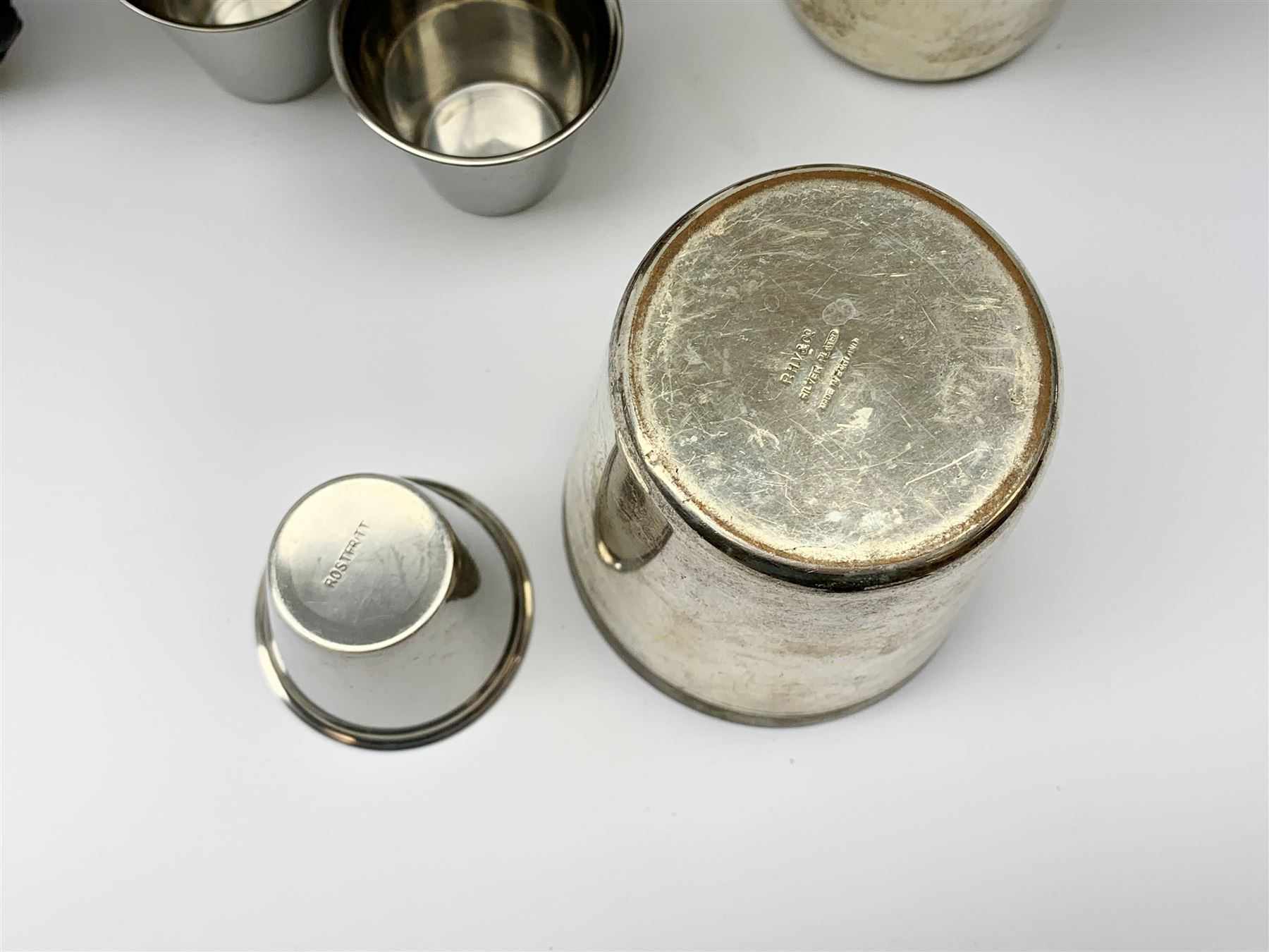 A silver plated set of four stirrup cuts with gilded interiors, by P H Vogel & Co, in brown leather case tooled in gilt J.R.S., each cup marked beneath P.H.V&Co Silver Plated Made in England, H8.5cm D7.5cm, together with a set of six stainless steel Swedish stirrup cups by Rostfritt, in green leather holder, each cup marked beneath Rosfritt, H4.5cm D5cm.