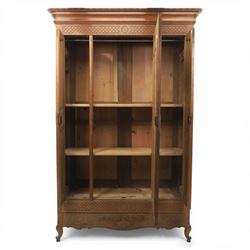 Early 20th century French oak triple door armoire, the moulded top above a frieze with carved lozenge decoration and central rosette, the central mirrored door enclosed by carved surround with floral crest, flanked by panelled doors with lattice carving, the base with shaped apron centred by carved basket motif, upon shaped cabriole supports