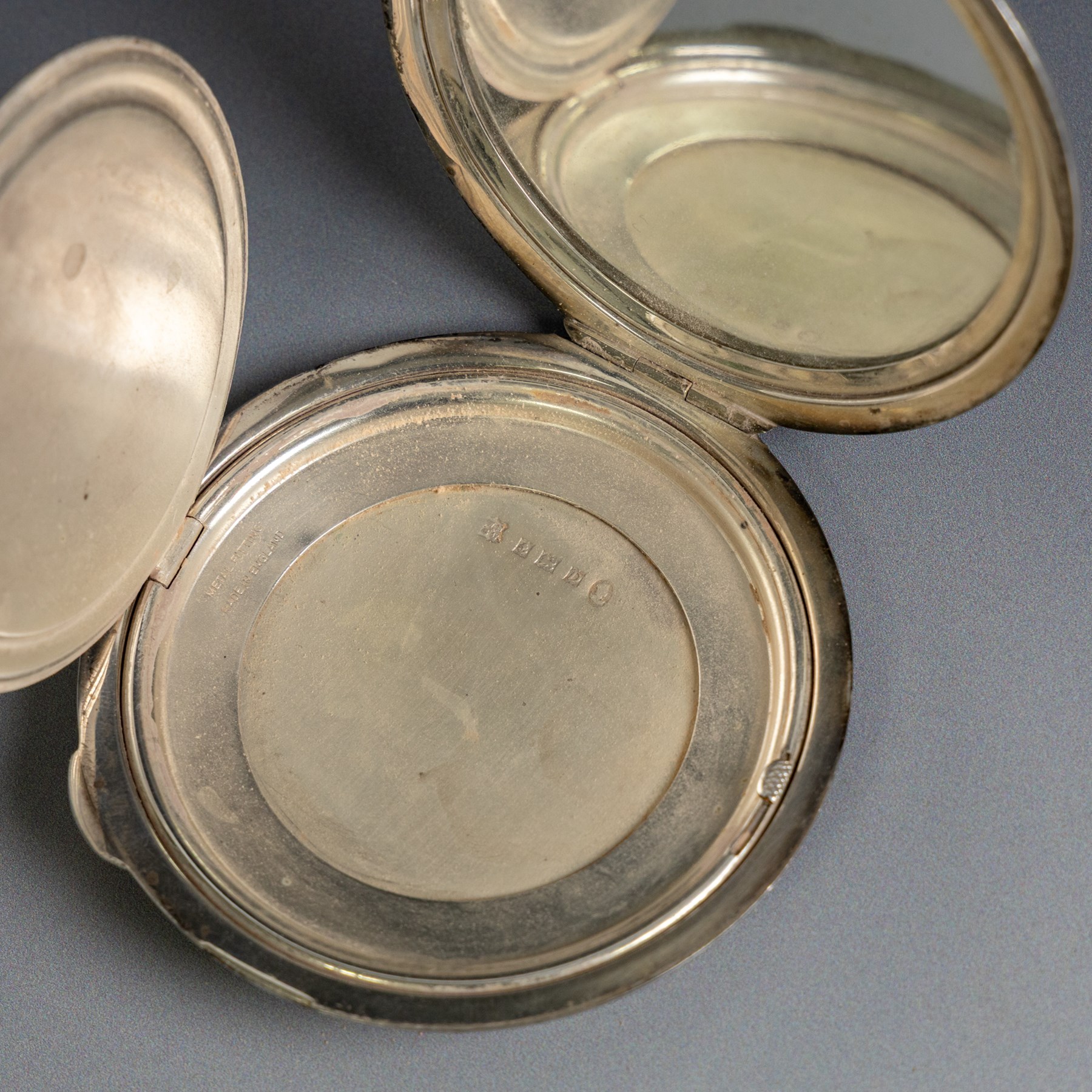 Two silver compact mirrors, comprising a Kigu powder compact with engine turned decoration and a compact mirror with floral decoration, both hallmarked