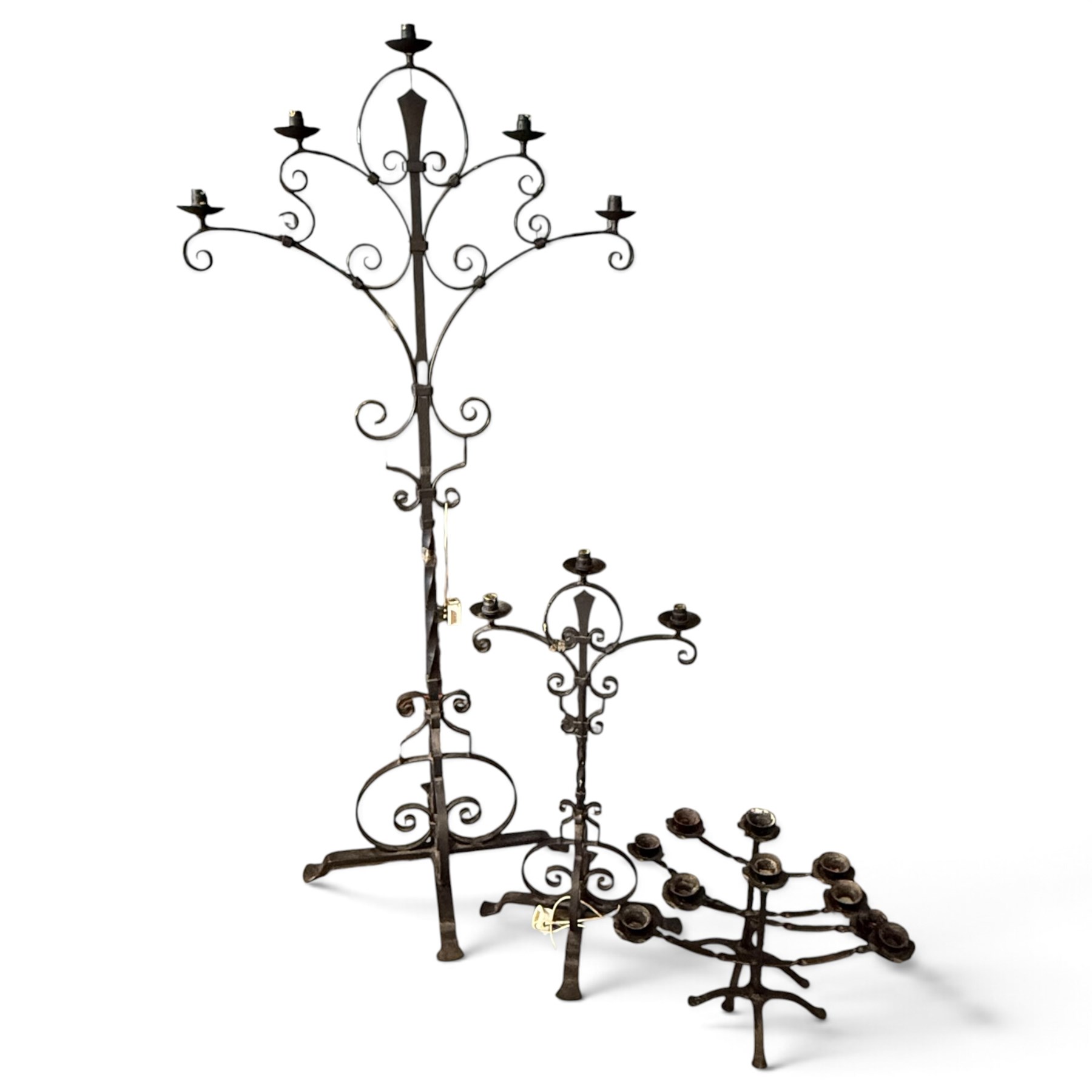 Collection of wrought iron candle stands, comprising five-light and three-light floor-standing candelabra with scrolling branches, and a pair of five-light table candelabra of naturalistic branching form