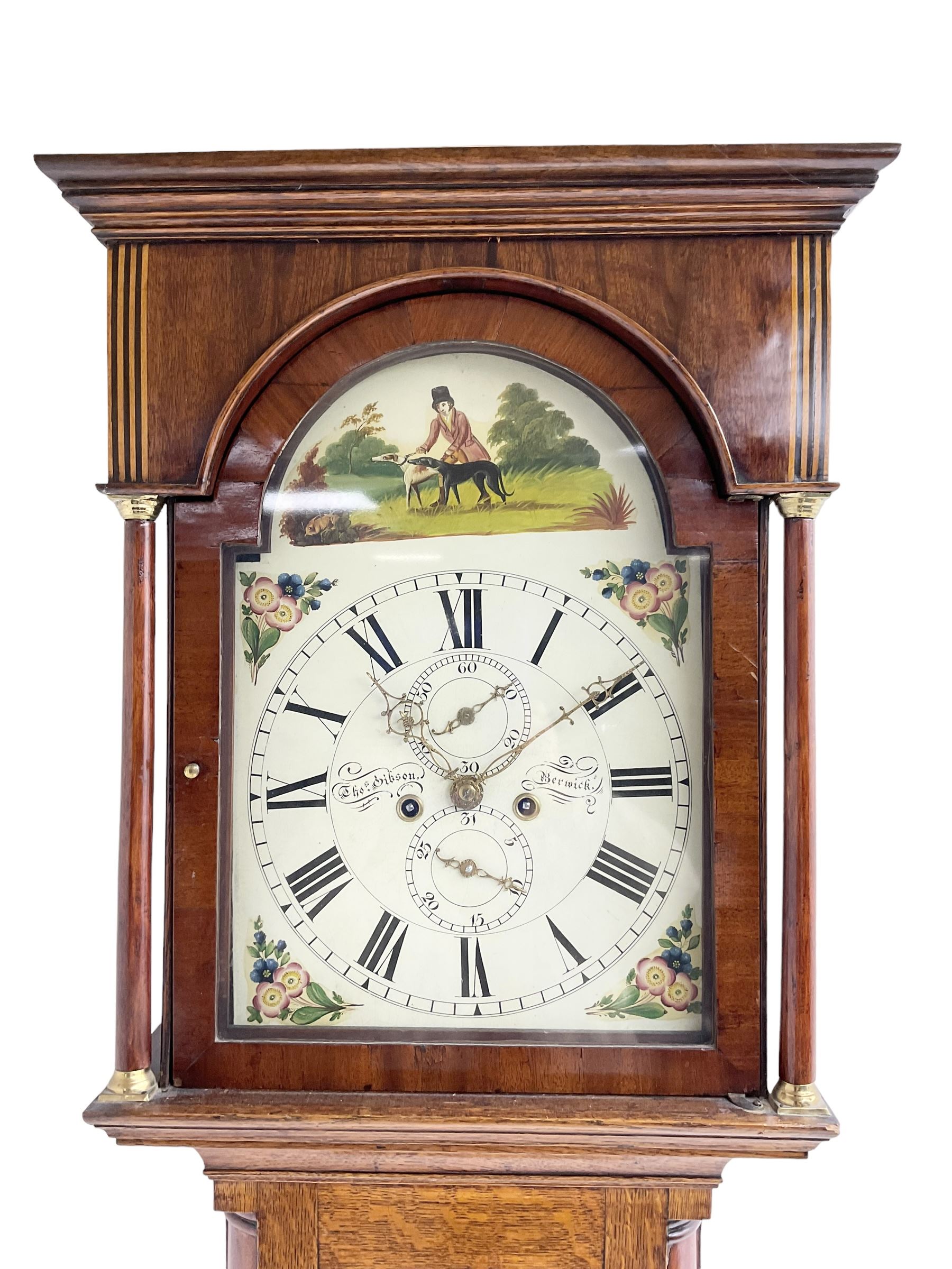 Thomas Gibson of Berwick - oak and mahogany 8-day longcase clock c 1860, with a flat topped pediment and recessed break arch door beneath, free standing pilasters with brass capitals, trunk with quarter columns to the corners and a wavy topped door, on a rectangular oak plinth with a shaped base,  painted dial with floral spandrels and a sporting scene to the break arch, Roman numerals, minute track and subsidiary seconds and date dial's, matching stamped brass hands pinned via a false plate to a rack striking movement, striking the hours on a bell. With weights, pendulum and key.   