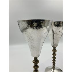 Pair of modern silver goblets by Stuart Devlin, the tapering cylindrical bowls each with spot hammered decoration and gilt interiors, the parcel gilt stems with signature textured detailing and six graduating knops, upon conforming spreading circular foot, hallmarked Stuart Devlin, London 1976, H17.7cm