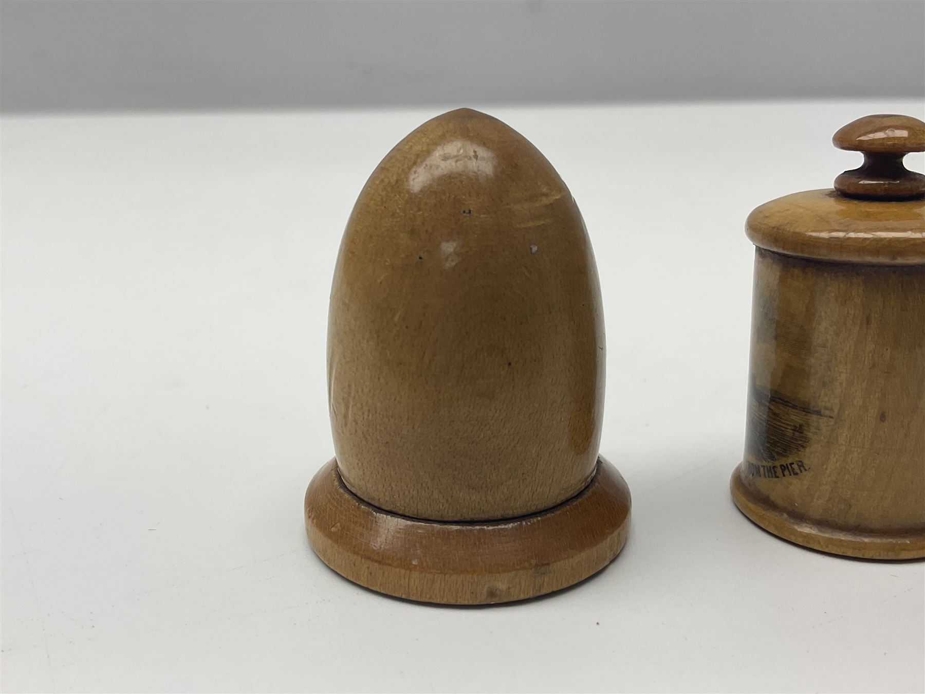 Six sewing related Mauchline ware comprising an oval reel box with internal label for Clark & Co's, tape measure, pin case and three thimble holders of ovoid form 