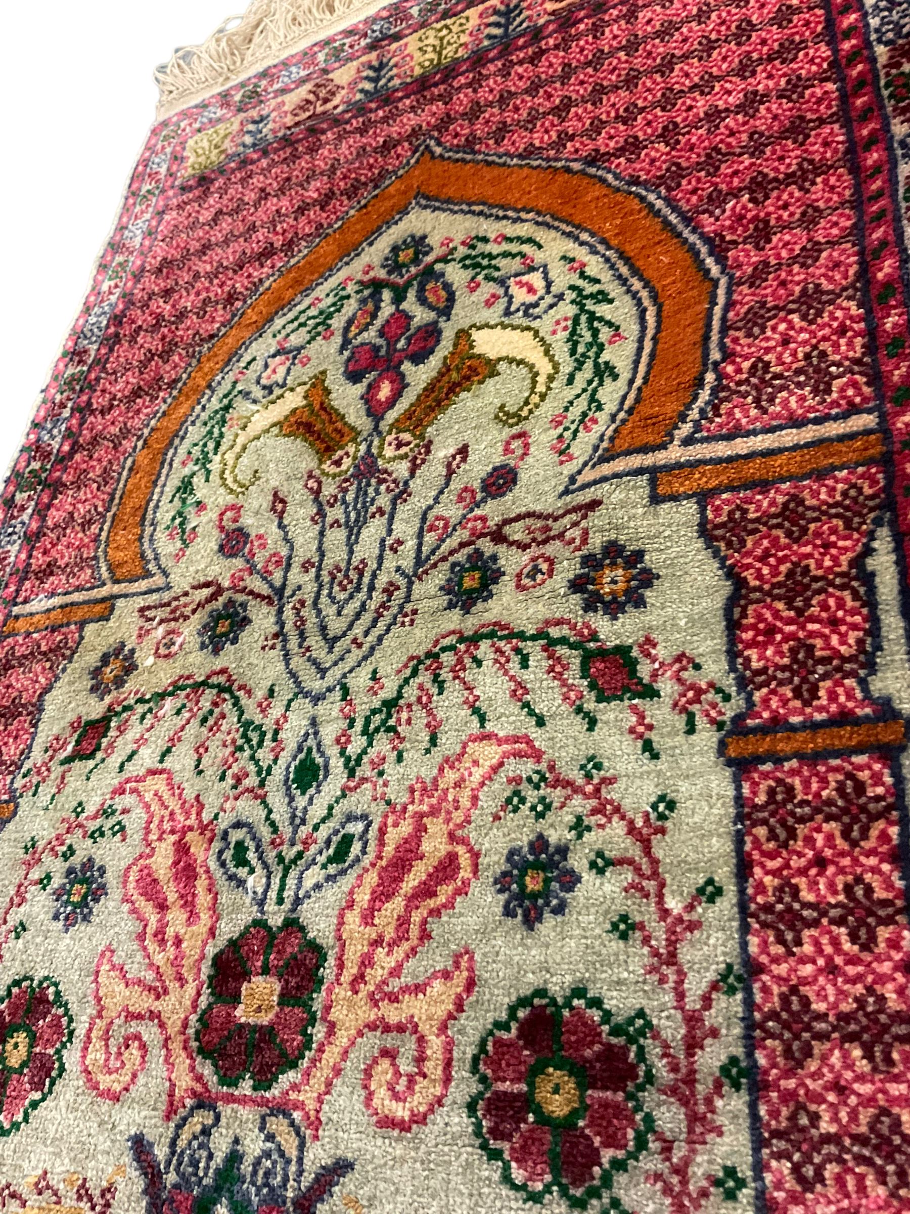 Small Persian magenta ground rug, central Mirab with flanking columns enclosing stylised urn motif with trailing foliage, the triple band border with plant motifs (86cm x 46cm); Persian red ground rug, two central floral medallions with extending flower heads, floral decorated border (106cm x 53cm) (2)