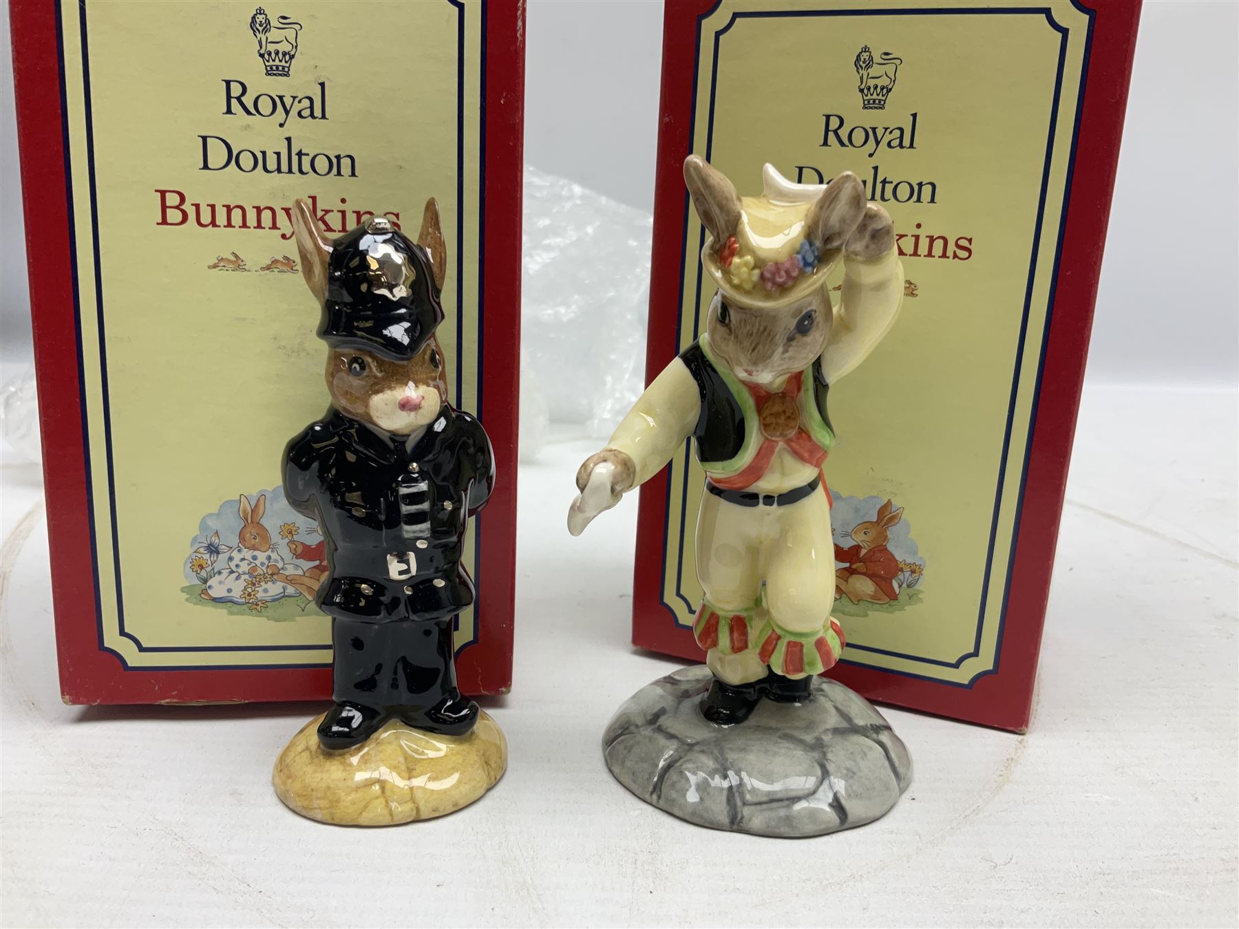 Royal Doulton The Mickey Mouse Collection Pluto figure, Coalport Characters The Snowman Dressing Up figure, three Royal Doulton Bunnykins figures comprising Policeman, Morris Danger and Eskimo, and display stand, Royal Doulton John Beswick Tiggy Winkle, Royal Albert Beatrix Potter Peter Postbag and three Goebel Hummel figures, all boxed