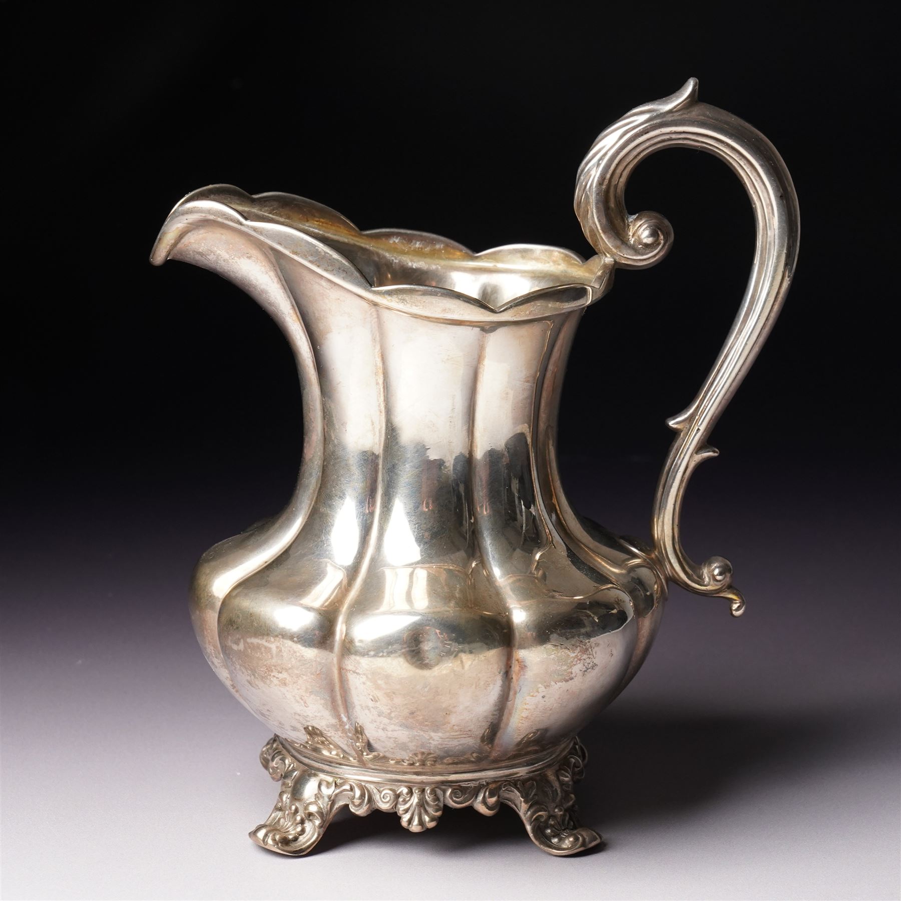 Victorian silver cream jug of panel sided baluster form with crimped rimand scroll handle on shaped supports London 1840 Maker Charles Gordon  