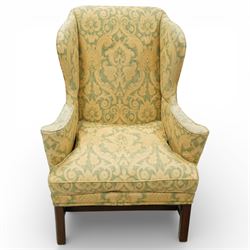 George III wing back armchair, the tall upholstered back with deep wings and gently shaped outline, padded arms flowing into the seat, loose cushion seat upholstered in a foliate patterned fabric, standing on square legs joined by stretchers