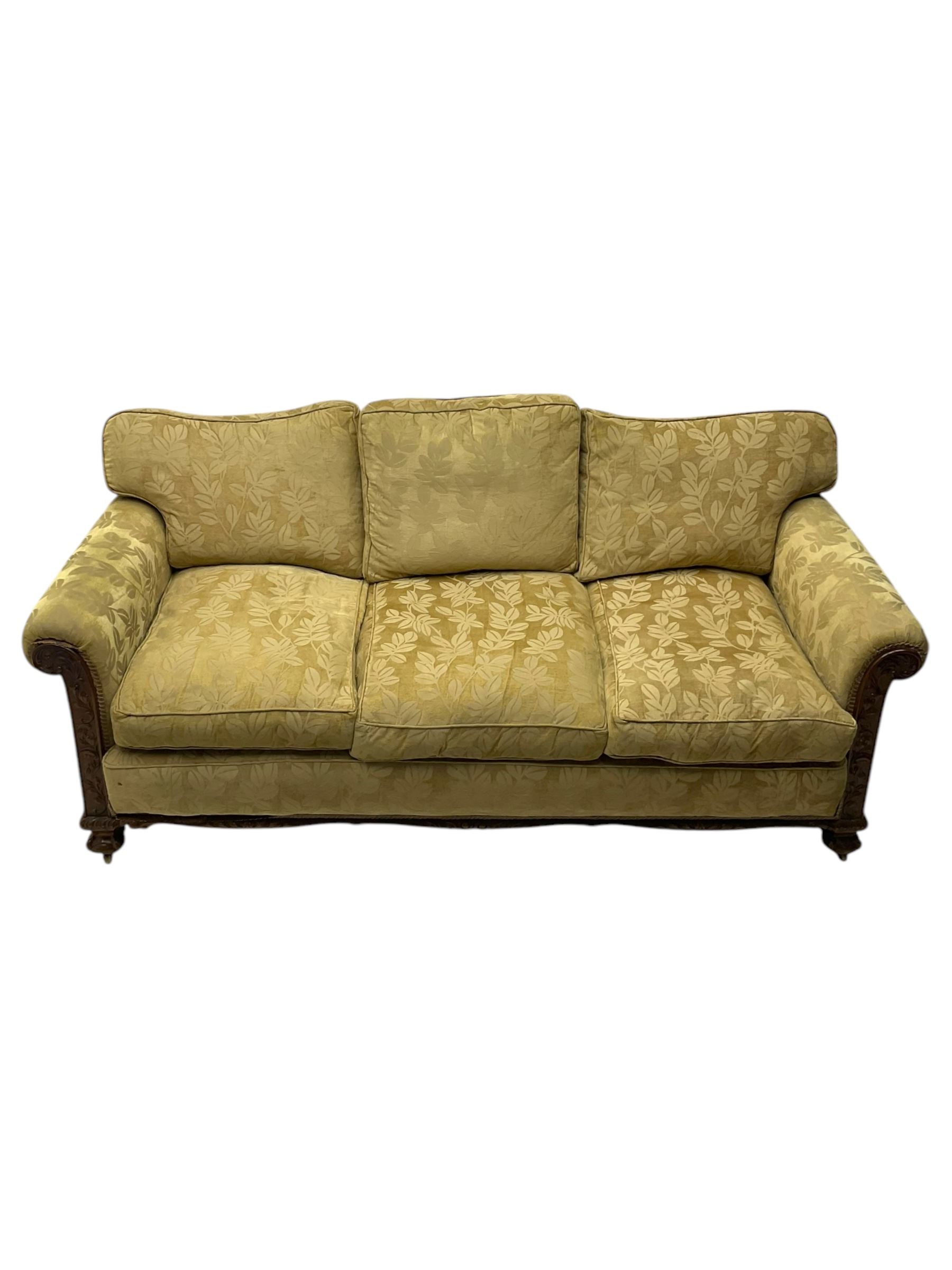 Early 20th century mahogany framed three-piece lounge suite - three-seat camelback sofa (W203cm, D105cm); pair of matching armchairs (W95cm, D96cm); upholstered in neutral foliate pattern fabric, carved with trailing leafy branches, ball and claw carved feet with brass castors 