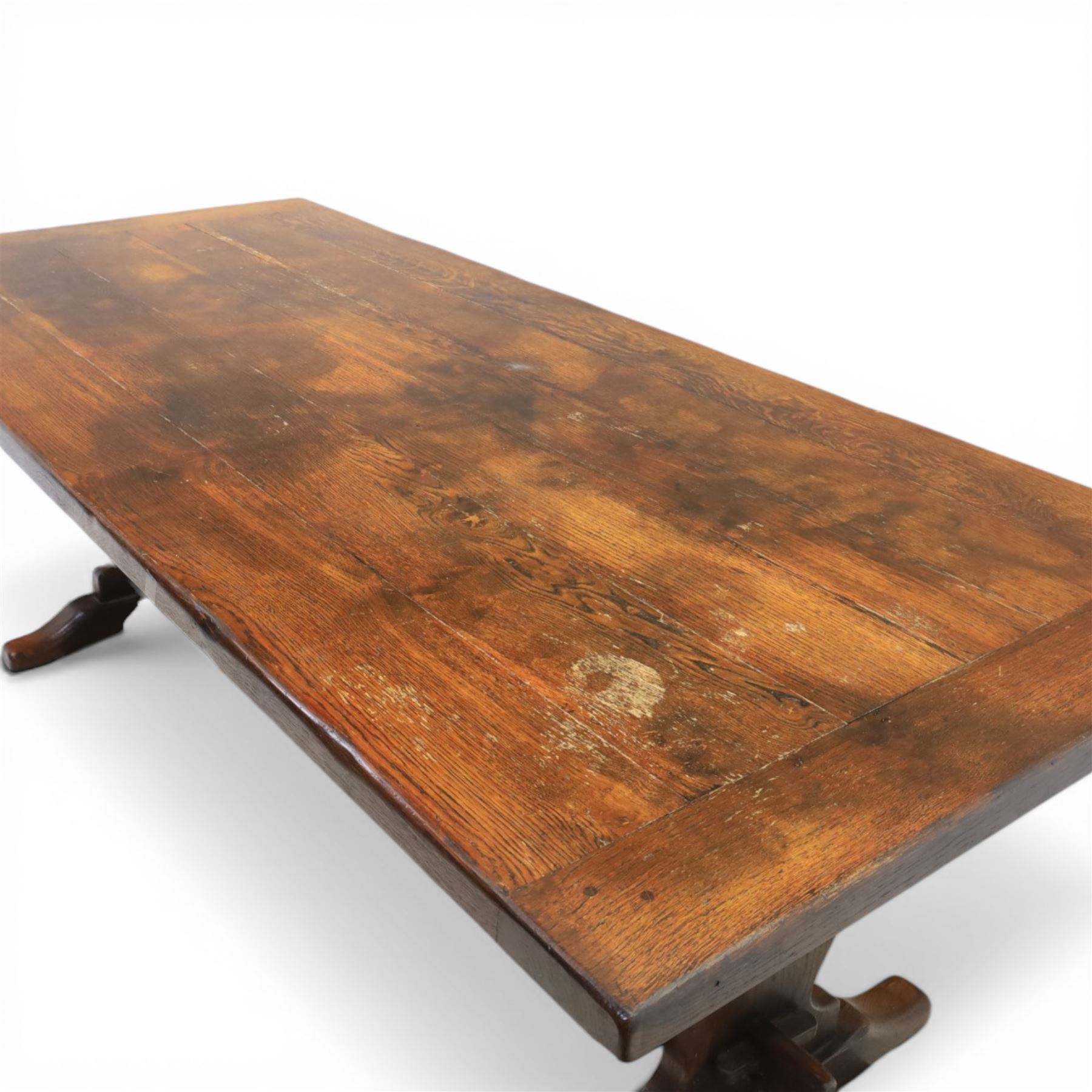 Carolean revival oak dining table and eight chairs (7+1), refectory table with rectangular boarded top and cleated ends, raised on shaped trestle end supports with central stretcher, accompanied by eight high-back chairs including a carver, leather upholstered panels and seats with studwork, on turned legs with stretchers.