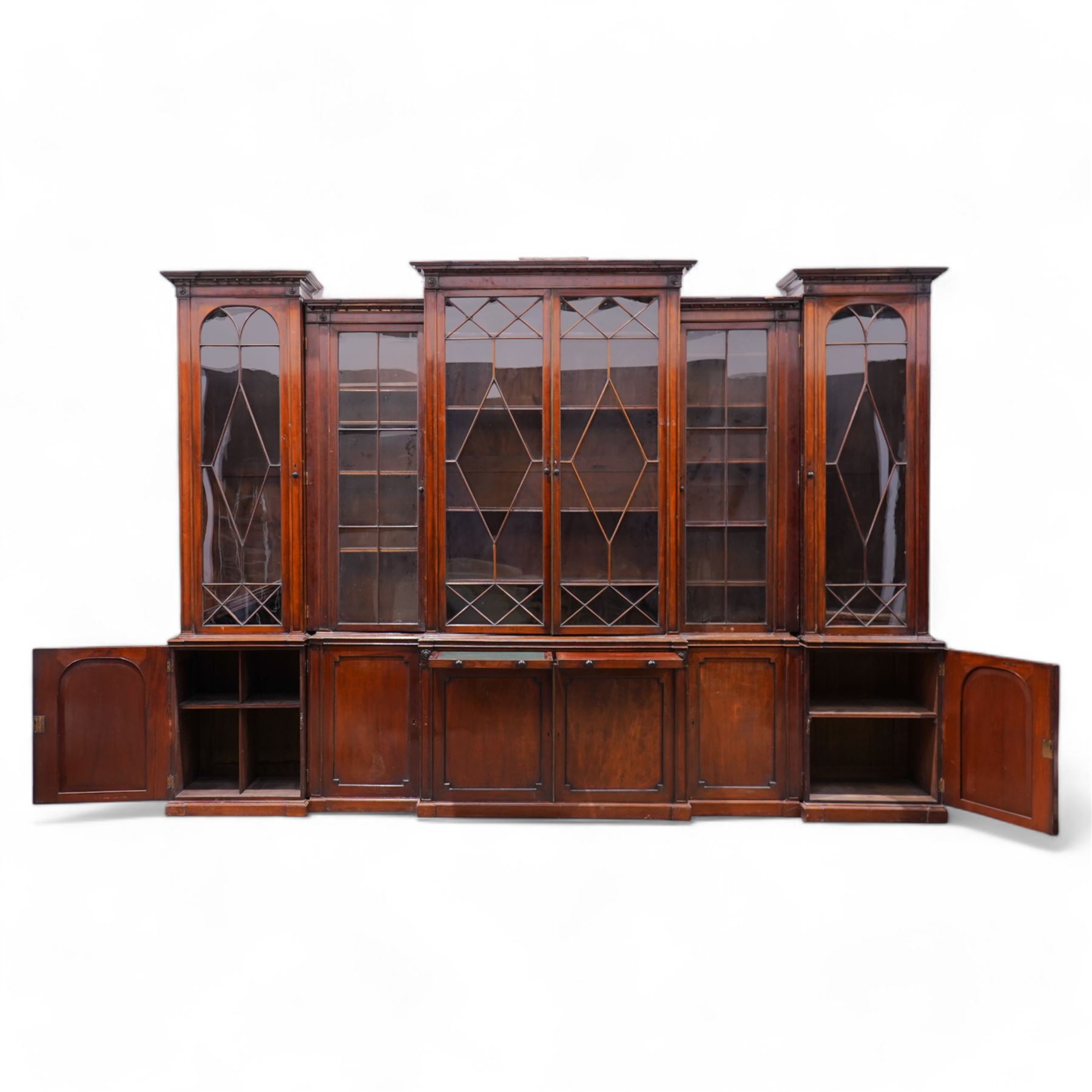 Large Georgian mahogany library bookcase, projecting moulded cornice with row of globular mounts, adjustable shelving enclosed by six astragal glazed doors, fitted with two slides and six panelled cupboard doors, two banks of five drawers, on moulded plinth base; together with two pairs of associated astragal glazed doors in mahogany, from the same property (W55.5cm x H168cm & W48cm x 168cm)