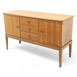 Gordon Russell - mid century modern teak sideboard, the rectangular top with rounded edges over twin cupboards and three central drawers, fitted with circular wooden pulls, on tapered supports, reflecting the firm’s commitment to simplicity and quality materials during the post-war design period