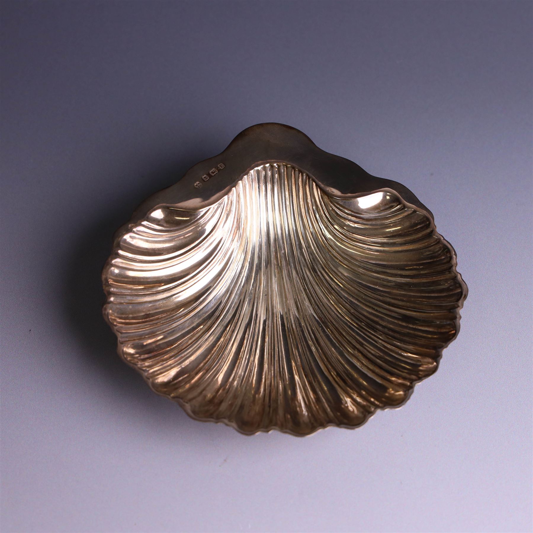 Edwardian silver butterdish in the form of a clam shell and upon four bun feet, hallmarked Williams Birmingham Ltd, Birmingham 1905, with a silver plated butter knife, contained within a fitted tooled leather case, width of dish 13cm