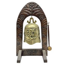 Chinese brass temple bell, decorated in high relief with a a dragon chasing a flaming pearl, within a carved floral hardwood stand, H36cm