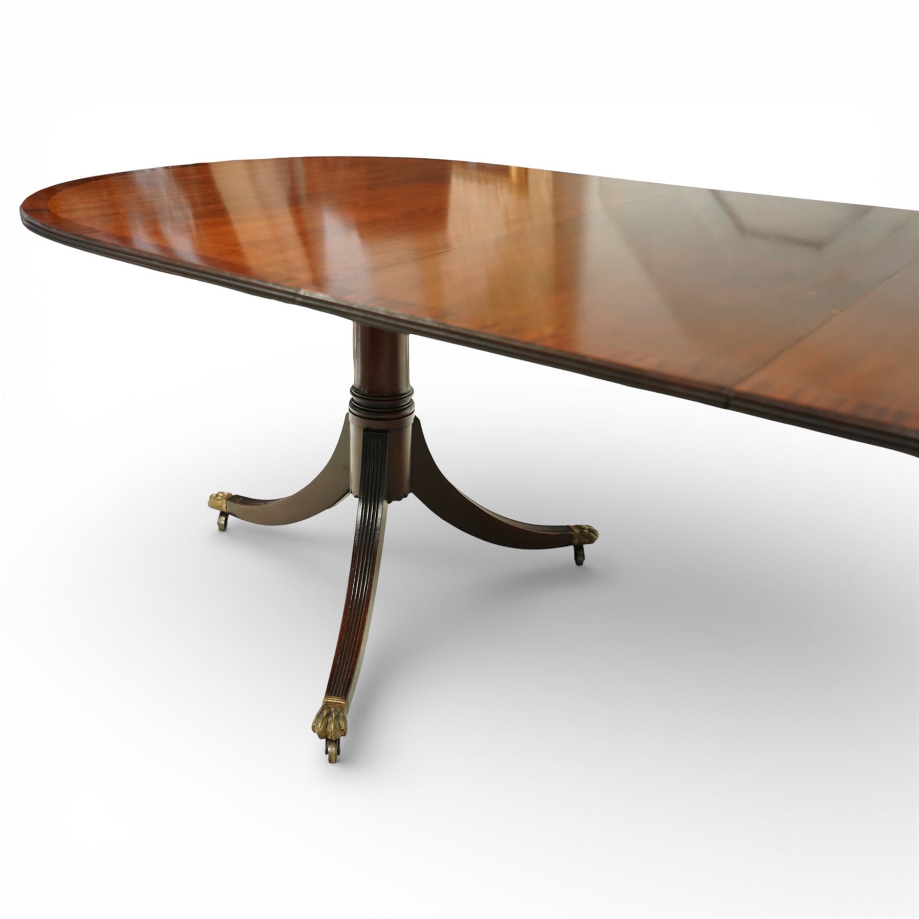 Arthur Brett & Sons - Regency design mahogany extending dining table and eight chairs, the oval top with rounded ends and two extension leaves, raised on twin pedestal supports with swept legs terminating in brass caps and castors, accompanied by a set of eight chairs comprising six single chairs and a pair of carvers, the chairs with curved backs and horizontal splat rails, upholstered seats, sabre legs and scrolling arms to the carvers
(Extends to 252cm)
(Chairs H 86cm, W 52cm)