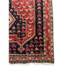 Persian indigo and crimson ground rug, the field with extending triple lozenge medallion, profusely decorated with bird motifs, triple band border with geometric design