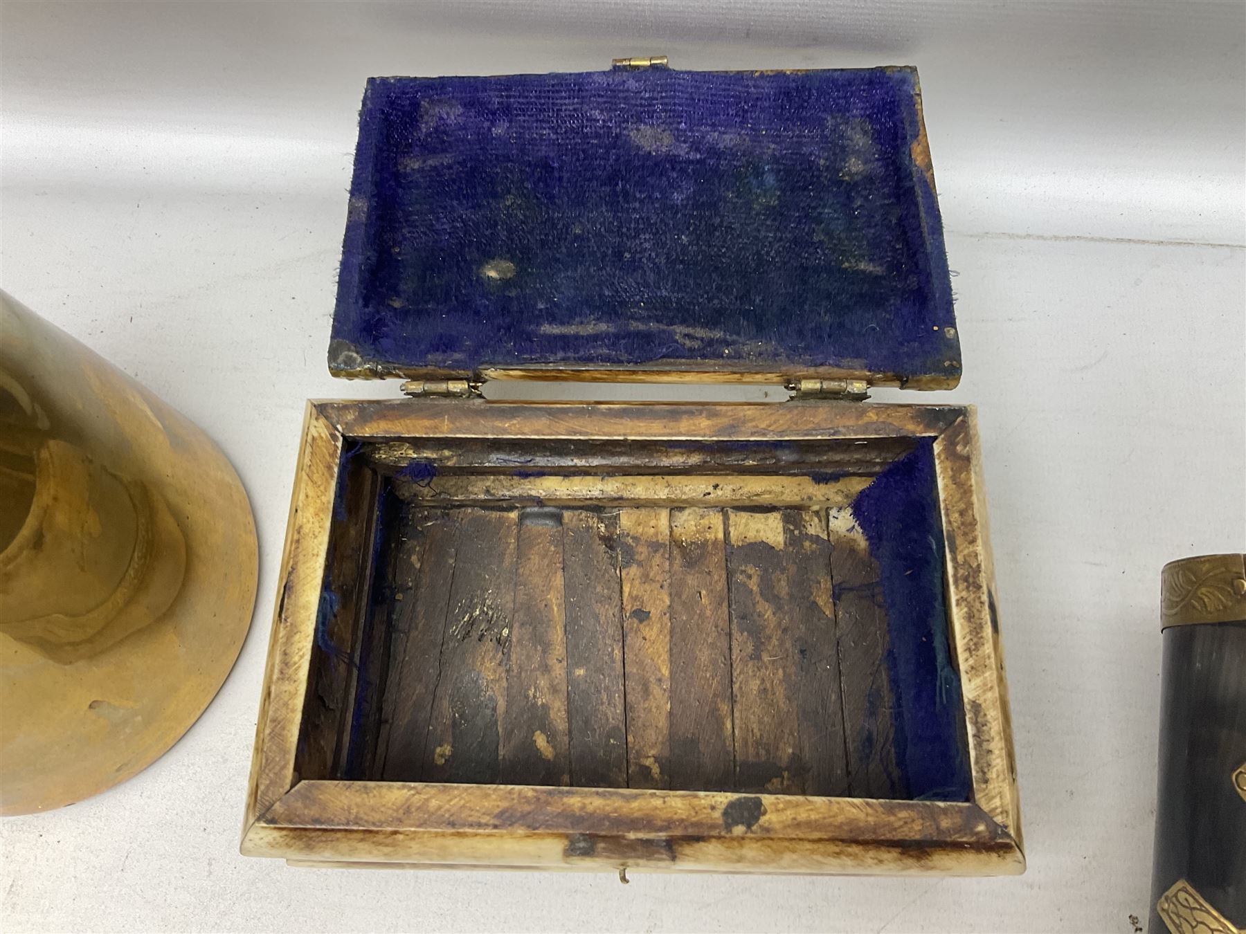 Swiss mountain hunters tobacco pipe with a horn mouthpiece, metal hinged pierced lid and brass chain, the black coated body adorned with small metal cow flowers, together with two other pipes and case, brass mounted horn, brass mounted bone box, carved mother of pearl handled knife and fork and brass jug