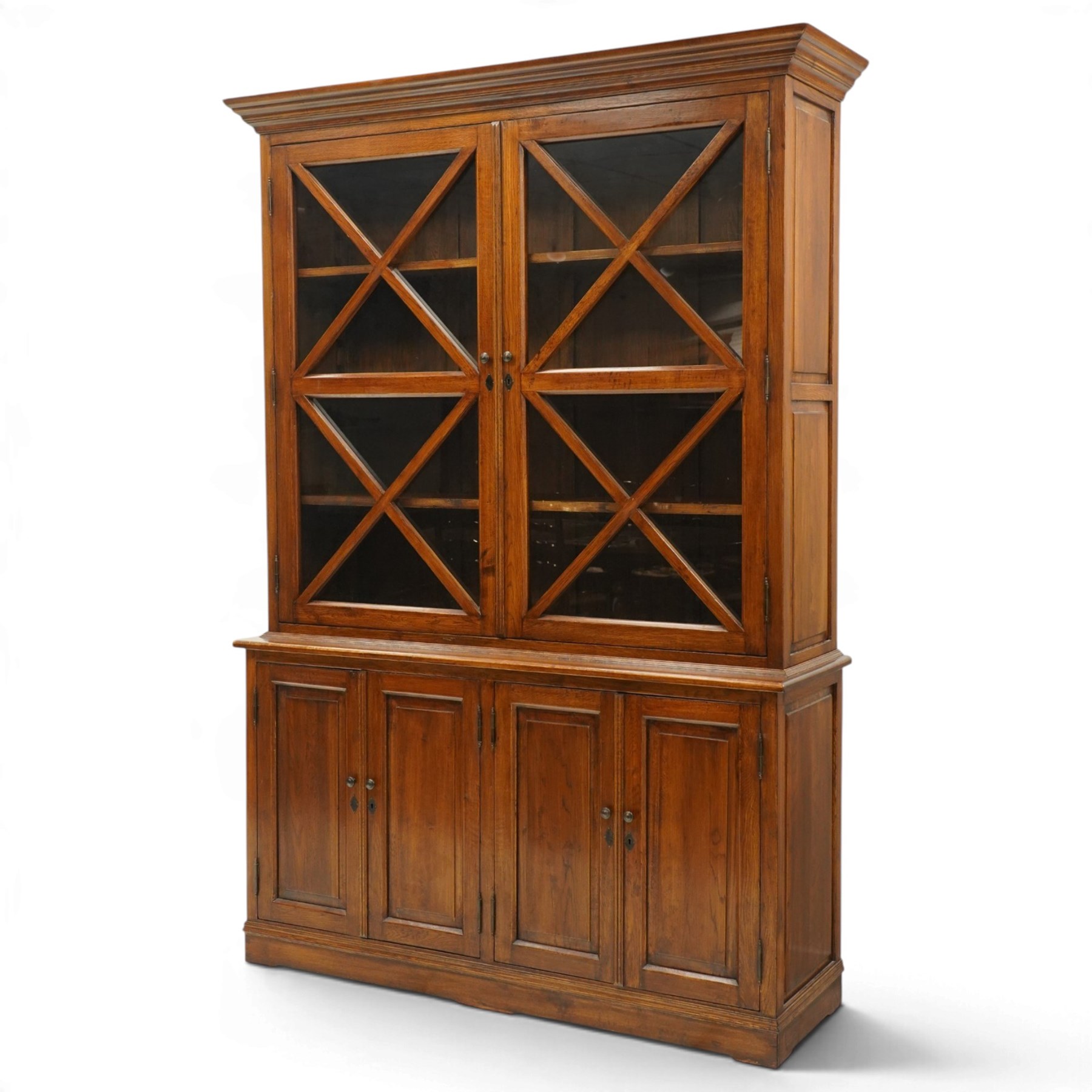 OKA - Glazed bookcase dark oark cabinet, the top with projecting cornice above astragal style glazed doors metal turned knobs, enclosing adjustable full length shelving, the lower half with two sets of twin cabinet doors housing fixed shelving, raised on a moulded plinth base  