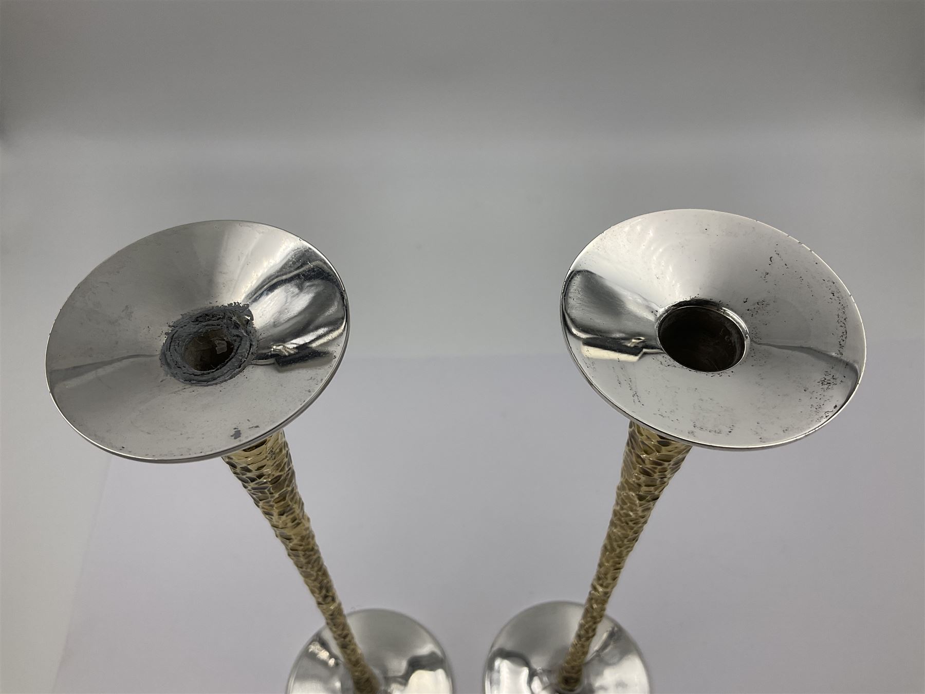 Pair of modern silver candlesticks by Stuart Devlin, the tapering parcel gilt stems with signature textured detailing, each supporting a fluted candle holder and upon a spreading circular foot, hallmarked Stuart Devlin, London 1973, H25cm