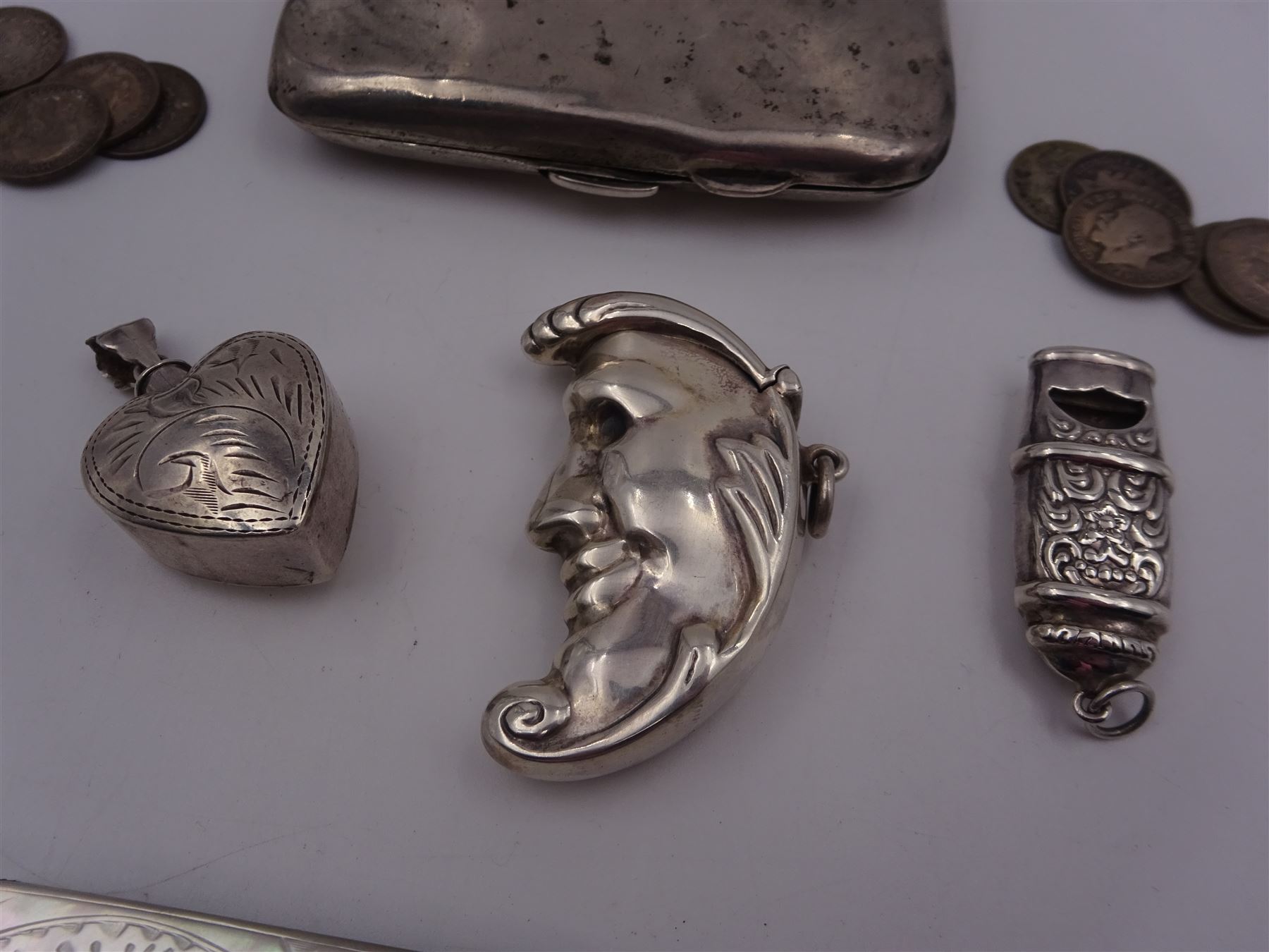Group of novelty silver items, comprising man in the moon vesta case, perfume pendant and a whistle, unmarked but test silver, together with a mother of pearl handled silver fruit knife, silver cigarette case, both hallmarked and a small quantity of silver threepences