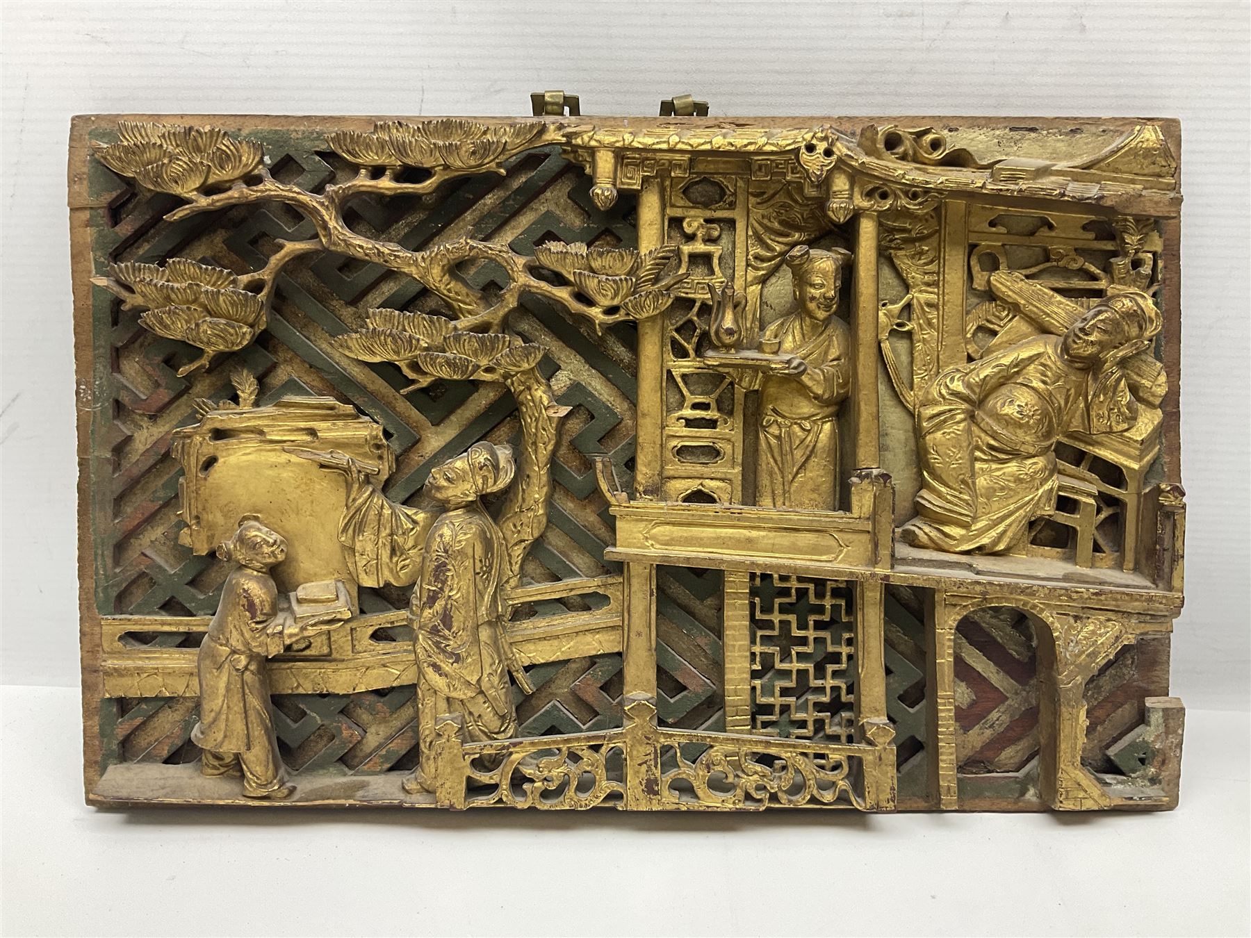 Two carved oriental wall hangings, the first example gilded depicting a temple and garden scene, the second figures in a garden, L49cm
