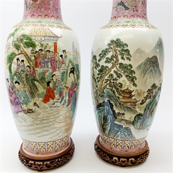 A pair of large Chinese famile rose style vases, one decorated with figural scene, the other with mountainous landscape, each with character mark beneath, upon pierced wooden stands, overall H67cm. 
