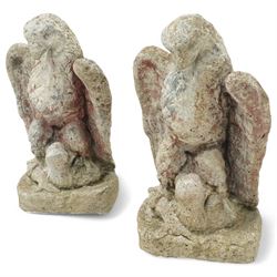 Pair of early 20th century painted stoneware eagle figures, modelled with wings partially spread and talons gripping prey, on a stone plinth