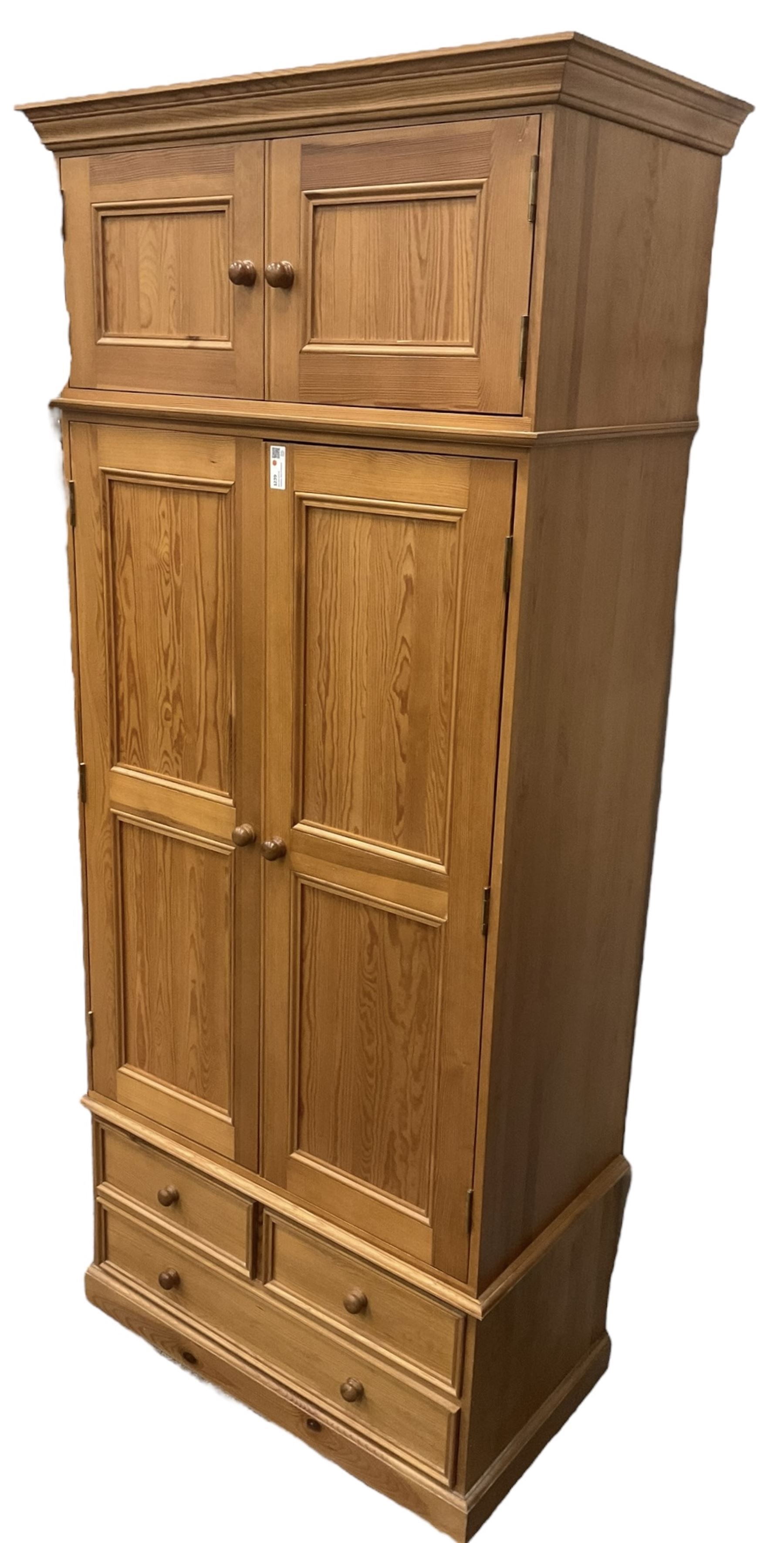 Solid pine double wardrobe, fitted with top box, enclosed by panelled doors, two short and one long drawer, on plinth base 