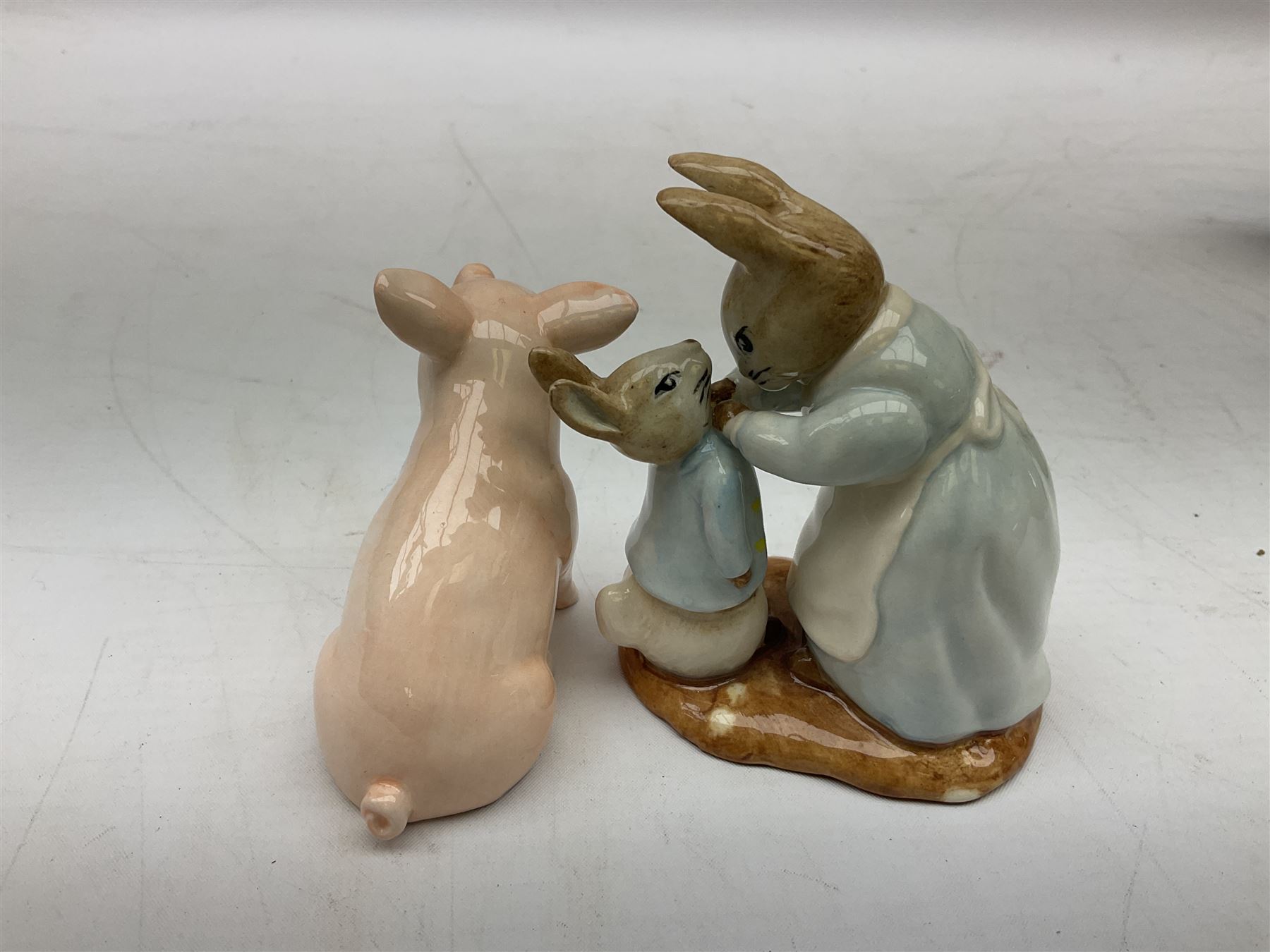 John Beswick figure of a seated piglet, Beswick Beatrix Potter Mrs Rabbit and Peter figure, and quantity of Sandland Character Ware jugs