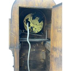 A mid-20th century English art-deco Grandmother clock with a mains powered electric movement chiming the hours and quarters on gong rods, in an oak case with an arched top, long trunk and short plinth on bracket feet, sliver effect chapter ring with Arabic numerals and silvered serpentine hands, with chime/silent facility.



