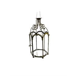 19th century brass and clear glass hexagonal hall lantern, with scrolling wire work open domed top over six arched panels, including a hinged door, the base enclosed with a circular glass panel on turned feet, H64cm