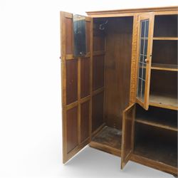 Edwardian oak glazed cabinet, moulded cornice above a panelled front and sides, fitted with lead glazed doors enclosing shelved interior, left side full length cupboard converted to enclose a gun cabinet, on a plain plinth base 