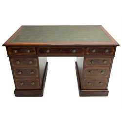 Edwardian inlaid mahogany twin pedestal desk, moulded rectangular top with satinwood band and green leather inset, fitted with nine drawers, the drawer fronts decorated with inlaid fan spandrels, circular lion mask and loop handles, on plinth base and ceramic castors