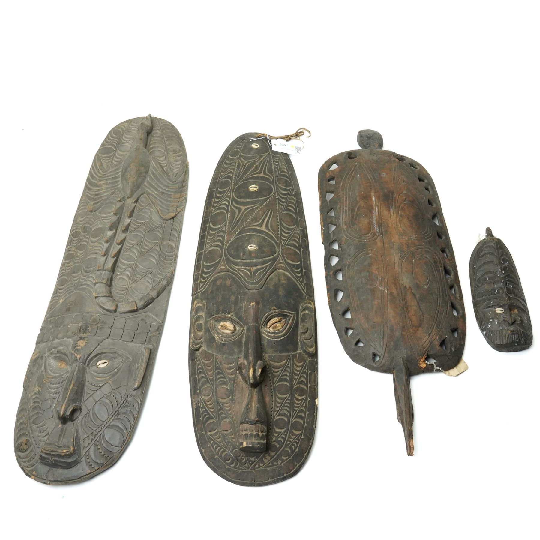 Papua New Guinea Middle Sepik carved sago plate with crocodile head handle L81cm, two Sepik masks/wall hangings inset with cowrie shells, larger 90cm and a small mask (4)