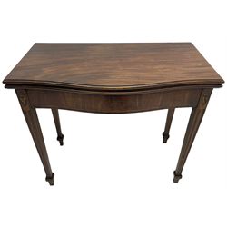 George III inlaid mahogany serpentine card table, the fold-over top with moulded edge supported by gate-leg action, the banded frieze with boxwood stringing, flanked by oval ebony inlay decoration with oak leaf and acorn motifs, raised on fluted supports