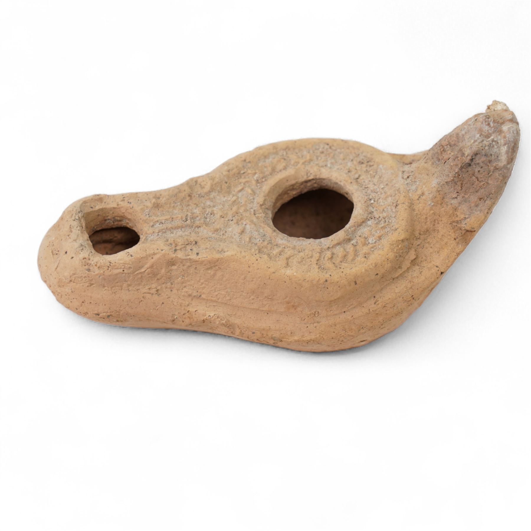 A group of four Byzantine terracotta oil lamps - Eastern Mediterranean, c.5th-7th century AD, comprising a group of mould-made slipper-form oil lamps, each with a rounded body, large central filling hole, and a short to elongated nozzle; including one with fine radiating linear decoration, and another preserving ancient use with traces of oil and wick residue within the burnished interior; together with a Crusader-period terracotta oil lamp (c.12th-13th century AD) of angular form with recessed panel decoration and a pierced handle moulded as a stylised animal head
Provenance: By the vendor’s repute, acquired/collected in the Middle East (Dead Sea area/Syria) in the 1960s