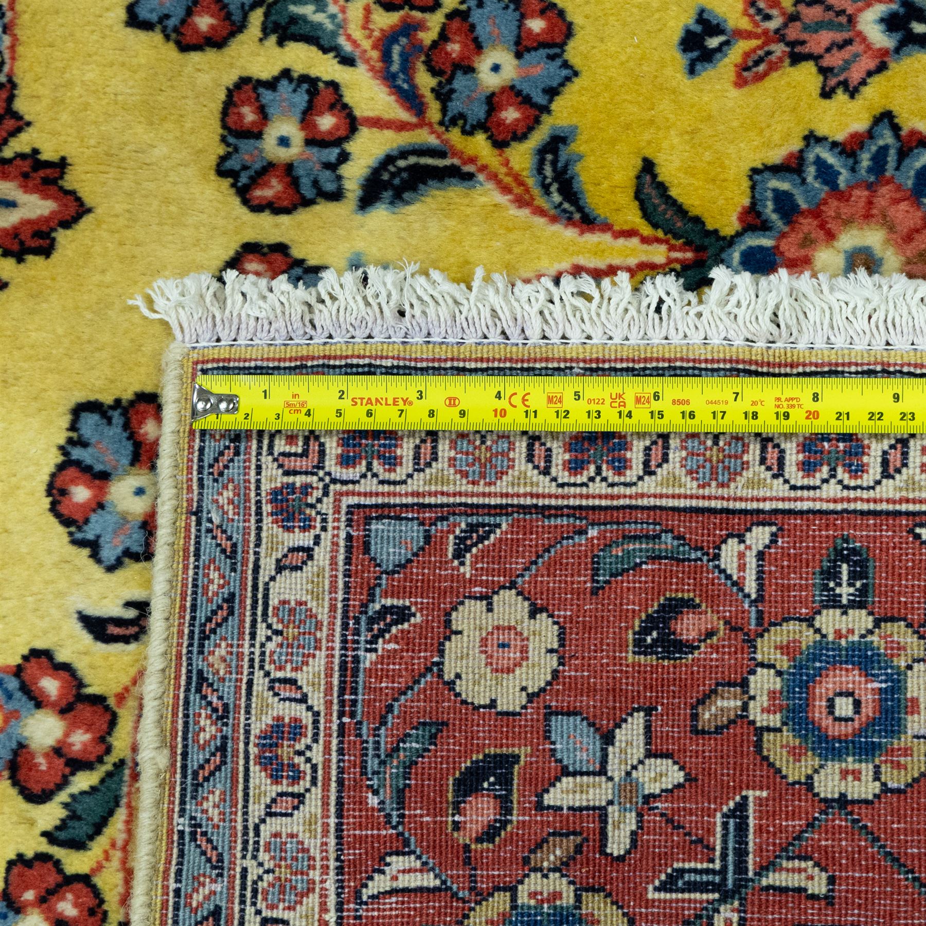 Persian Sarough hand-knotted carpet, golden yellow ground, with an all-over floral design centred by a small floral motif, the field decorated with mirrored flowering sprays, scrolling vines and dark navy foliate corner motifs, enclosed by a terracotta border with repeating flowerheads and palmettes, flanked by narrow guard stripes, with cotton fringes